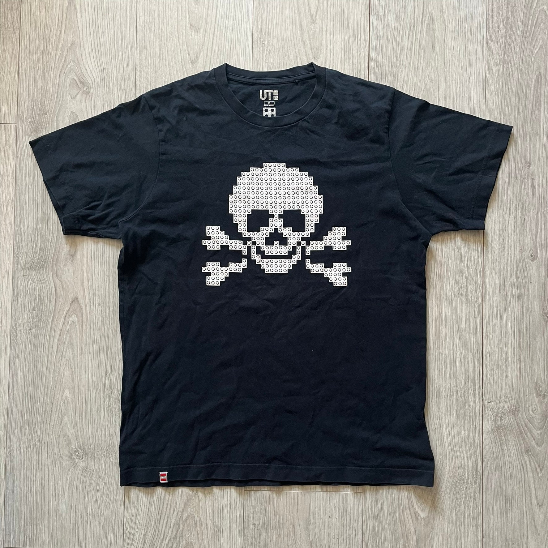 Black boxer briefs with a white pixelated skull design on a wooden floor.