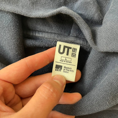 Uniqlo UT 2018 Hokusai The Great Wave Hoodie is a thick, dark navy hoodie featuring a large print of "The Great Wave off Kanagawa" by Hokusai across the lower front, created in collaboration with the Museum of Fine Arts Boston. It includes side pockets.