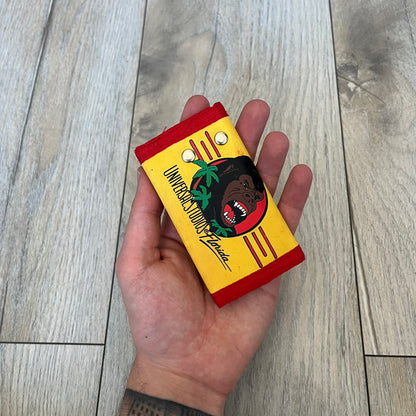 Universal Studios Florida 1985 King Kong Key Holder Wallet is a yellow wallet with red trim featuring King Kong-themed graphics on both sides. One side displays a King Kong illustration with Universal Studios Florida branding, while the other features the King Kong logo, palm tree graphics, and 1985 licensing details. The interior includes a storage pocket and four metal key holders for organizing keys.
