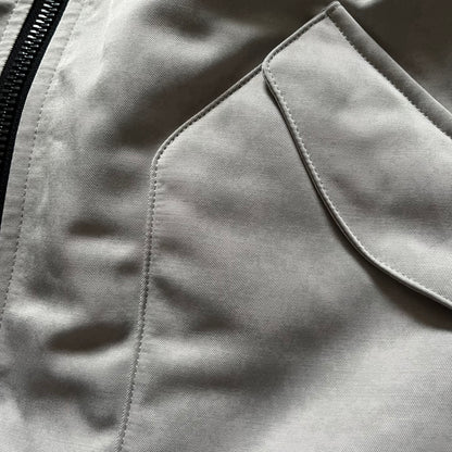 Unknown London Reversible Bomber Jacket crafted from padded polyester with a relaxed fit. One side features black matte fabric with embroidered logo, snakes, and multicolor detailing, plus arm patch and chest logo. The reverse side is beige with subtle chest embroidery in a softer cotton-like texture, offering two distinct styling options.