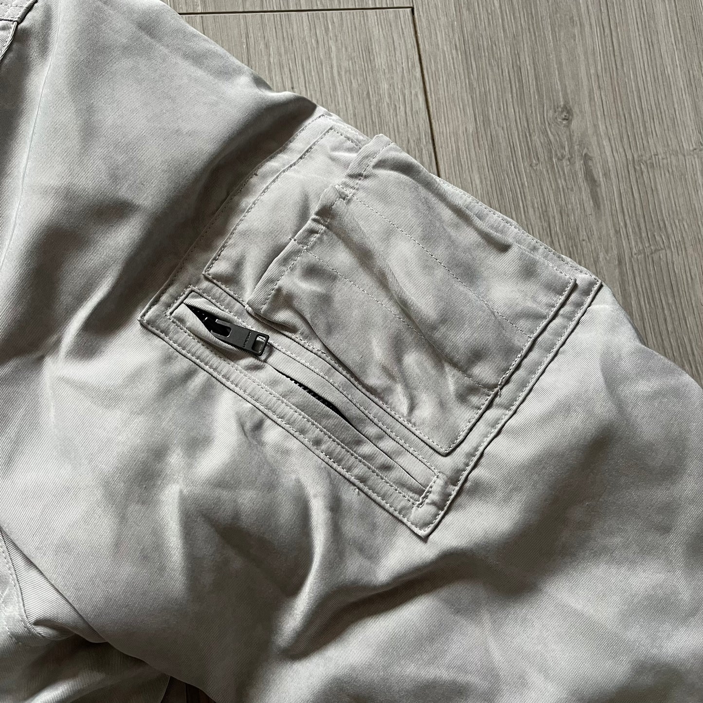 Unknown London Reversible Bomber Jacket crafted from padded polyester with a relaxed fit. One side features black matte fabric with embroidered logo, snakes, and multicolor detailing, plus arm patch and chest logo. The reverse side is beige with subtle chest embroidery in a softer cotton-like texture, offering two distinct styling options.