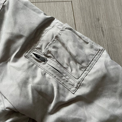 Unknown London Reversible Bomber Jacket crafted from padded polyester with a relaxed fit. One side features black matte fabric with embroidered logo, snakes, and multicolor detailing, plus arm patch and chest logo. The reverse side is beige with subtle chest embroidery in a softer cotton-like texture, offering two distinct styling options.