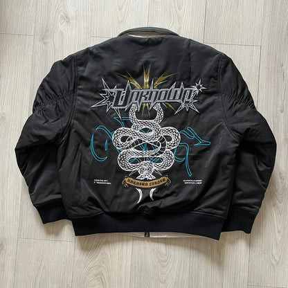Unknown London Reversible Bomber Jacket crafted from padded polyester with a relaxed fit. One side features black matte fabric with embroidered logo, snakes, and multicolor detailing, plus arm patch and chest logo. The reverse side is beige with subtle chest embroidery in a softer cotton-like texture, offering two distinct styling options.