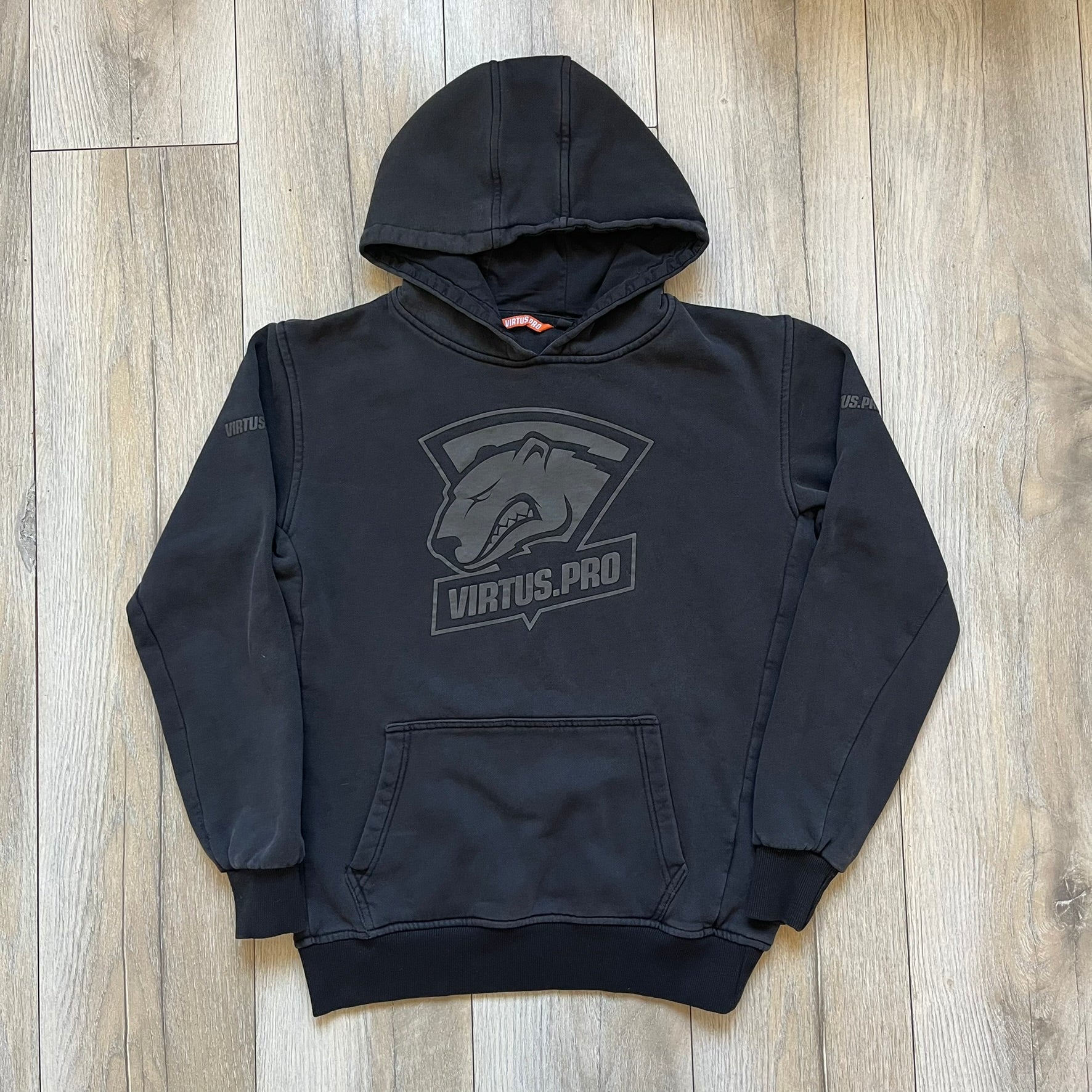 Virtus Pro 2020s Washed Black Hoodie is a black pullover hoodie featuring the Virtus.Pro logo on the front. Made from soft, high-quality materials, it offers a comfortable fit with durability suitable for casual wear or gaming. This hoodie was released in the 2020s as official Virtus.Pro esports merchandise.