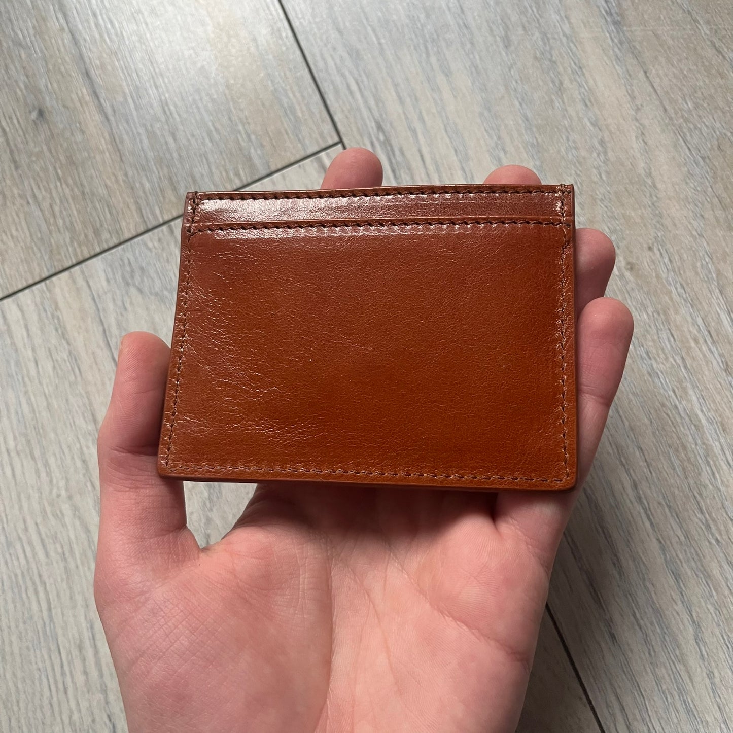 Vivienne Westwood Brown Flat Card Holder is crafted from buffed leather in a camel brown tone with logo hardware at the front. It features four card slots, a central note compartment, black twill lining, and an interior leather Vivienne Westwood tab with a material tag. Made in Italy, the card holder comes with the original box and tags. 252314M163098