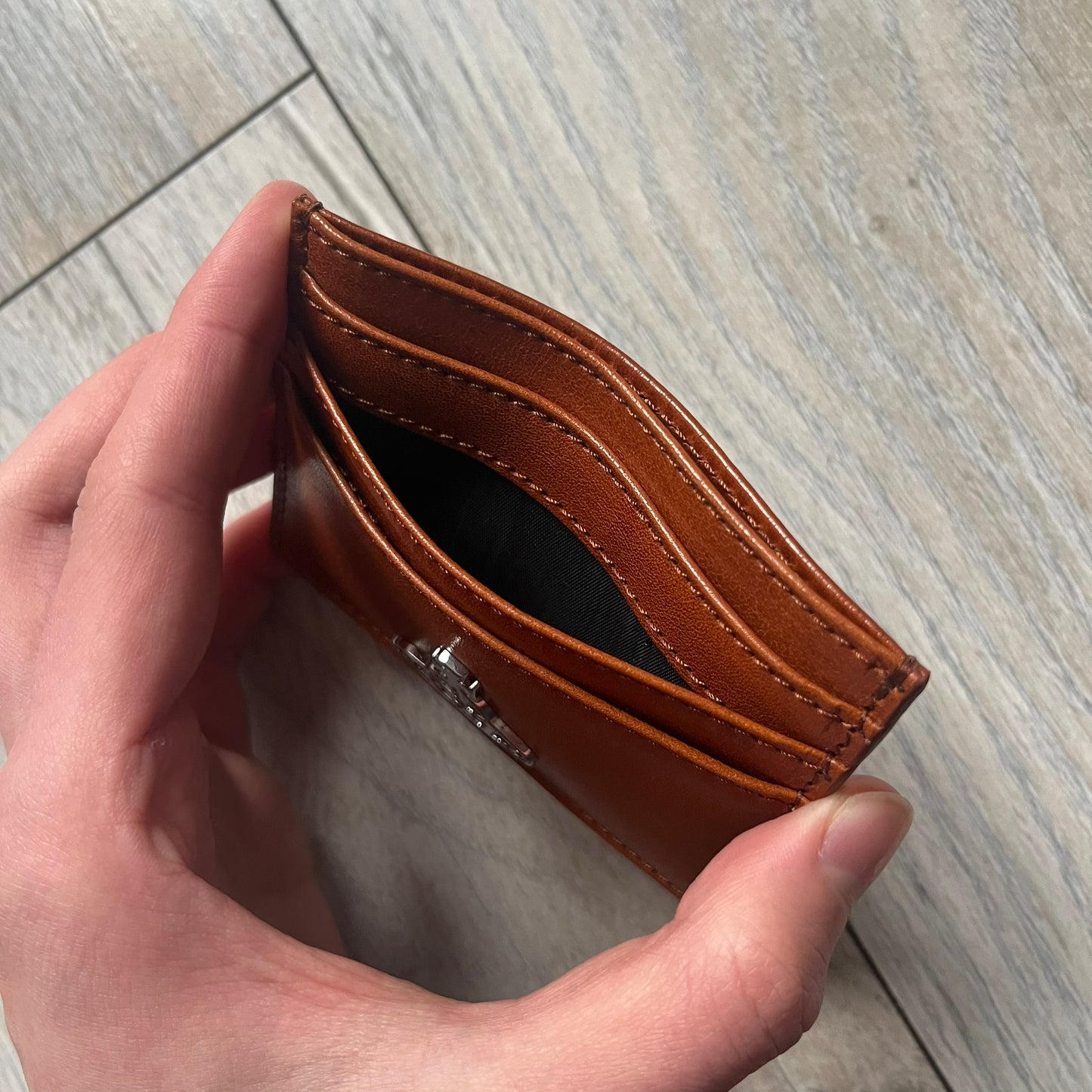 Vivienne Westwood Brown Flat Card Holder is crafted from buffed leather in a camel brown tone with logo hardware at the front. It features four card slots, a central note compartment, black twill lining, and an interior leather Vivienne Westwood tab with a material tag. Made in Italy, the card holder comes with the original box and tags. 252314M163098