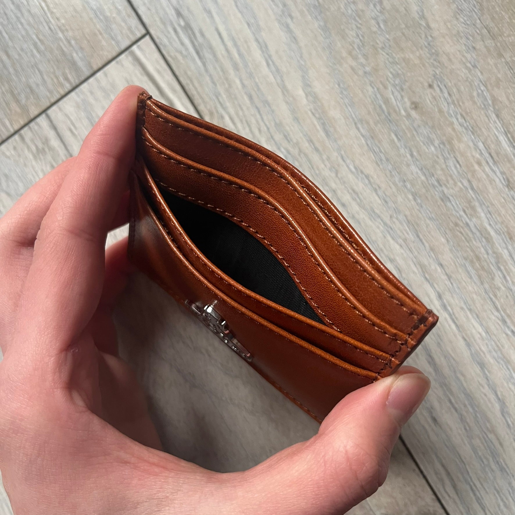 Vivienne Westwood Brown Flat Card Holder is crafted from buffed leather in a camel brown tone with logo hardware at the front. It features four card slots, a central note compartment, black twill lining, and an interior leather Vivienne Westwood tab with a material tag. Made in Italy, the card holder comes with the original box and tags. 252314M163098