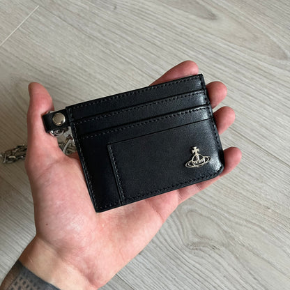 Vivienne Westwood Flat Chain Card Holder in black leather, featuring the signature silver Orb emblem on the corner. Designed with four compartments - three main slots and one smaller front pocket. Completed with a flat chain and an engraved Vivienne Westwood loop for a refined finish.