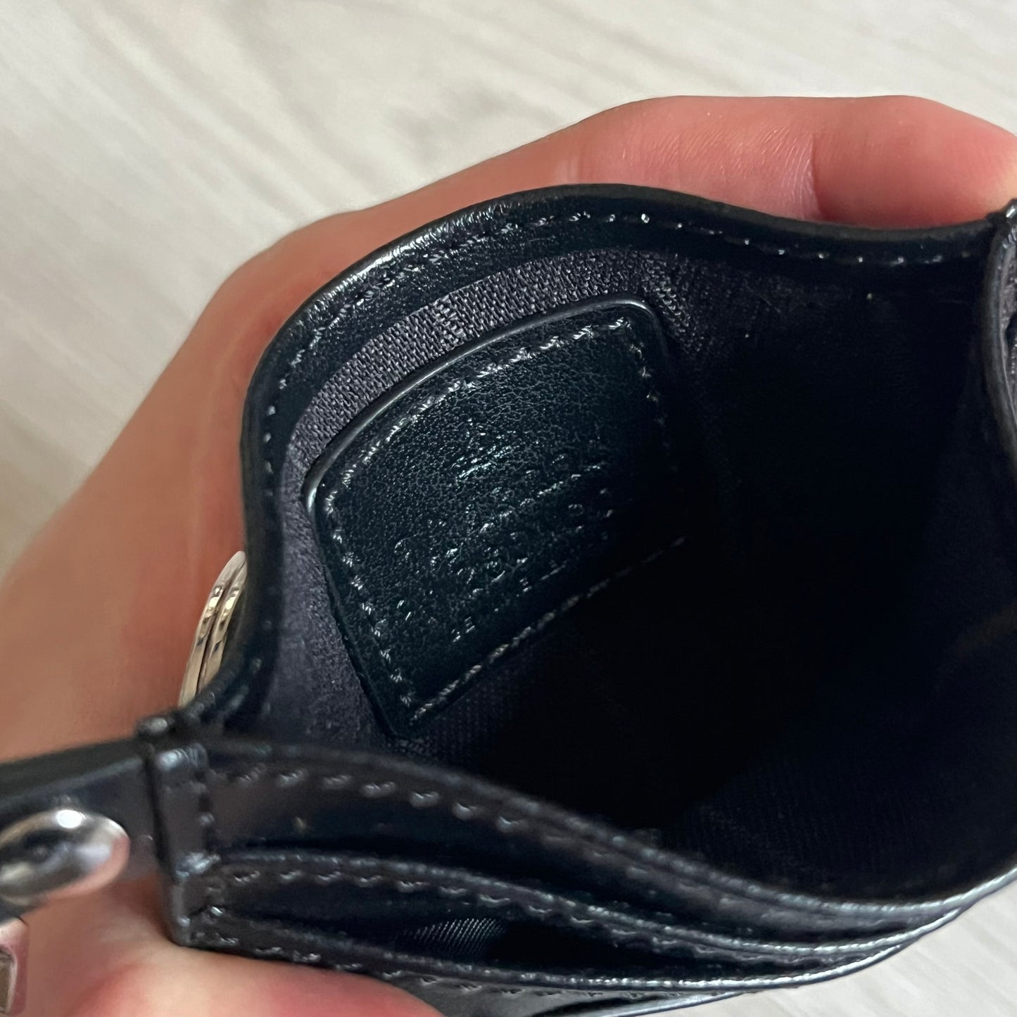 Vivienne Westwood Flat Chain Card Holder in black leather, featuring the signature silver Orb emblem on the corner. Designed with four compartments - three main slots and one smaller front pocket. Completed with a flat chain and an engraved Vivienne Westwood loop for a refined finish.