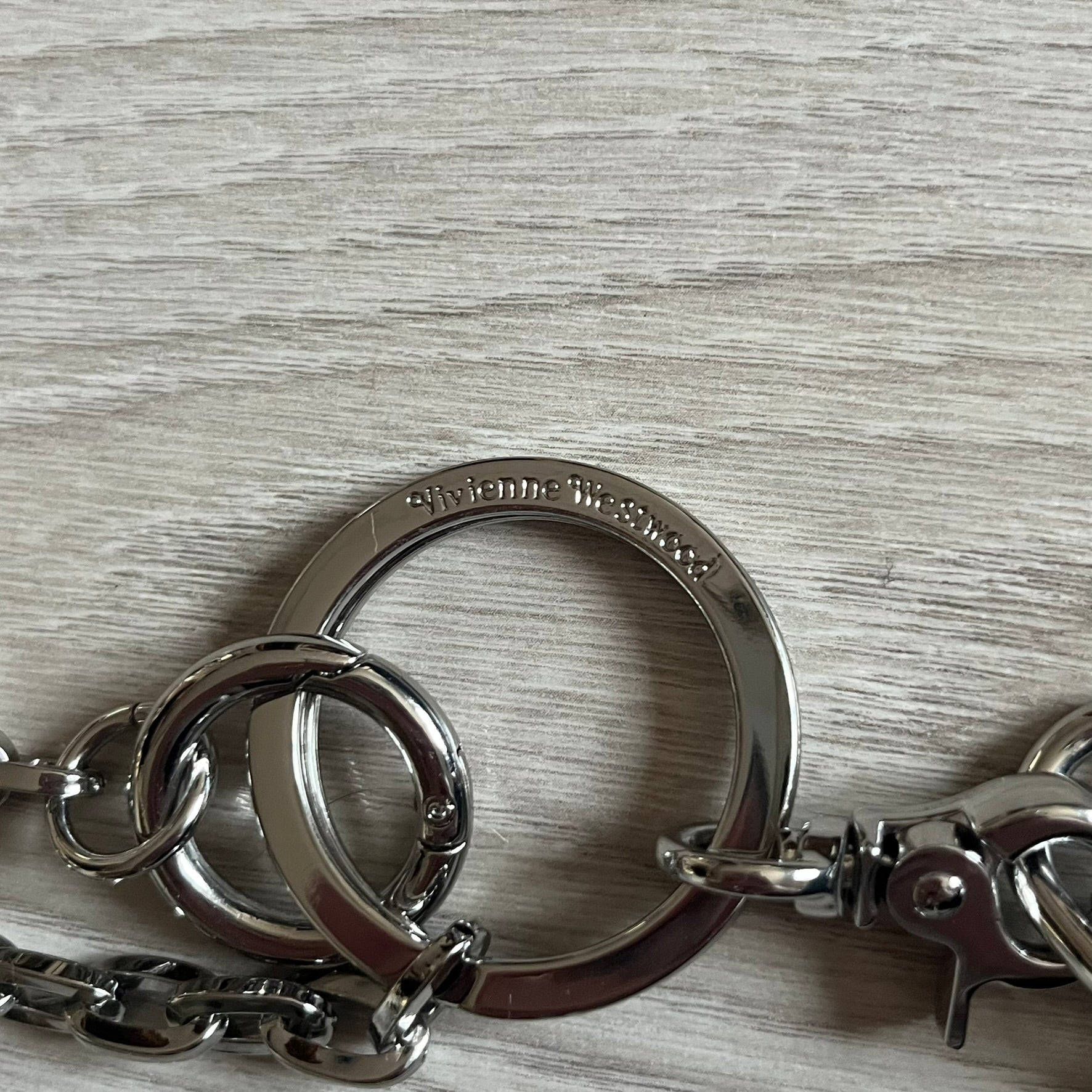 Vivienne Westwood Flat Chain Card Holder in black leather, featuring the signature silver Orb emblem on the corner. Designed with four compartments - three main slots and one smaller front pocket. Completed with a flat chain and an engraved Vivienne Westwood loop for a refined finish.