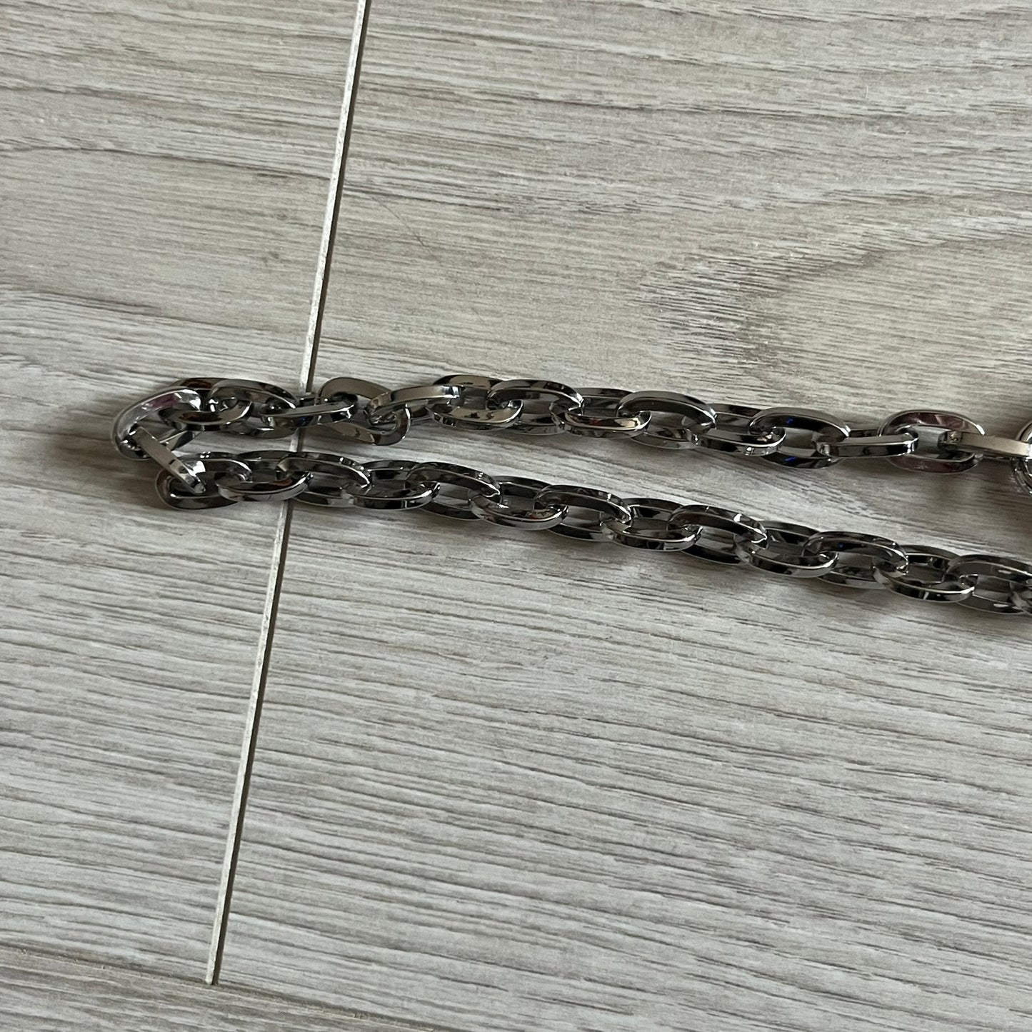 Vivienne Westwood Flat Chain Card Holder in black leather, featuring the signature silver Orb emblem on the corner. Designed with four compartments - three main slots and one smaller front pocket. Completed with a flat chain and an engraved Vivienne Westwood loop for a refined finish.