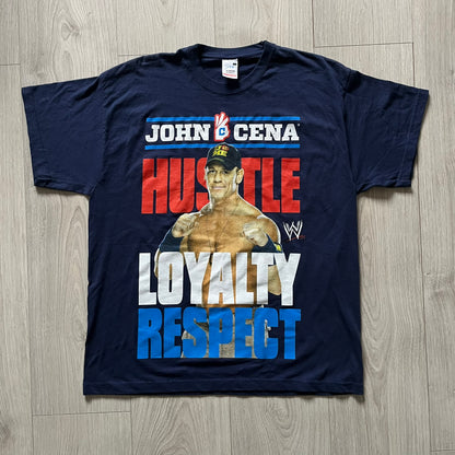 WWE John Cena “Hustle Loyalty Respect” Tee in navy, printed on a classic Screen Stars blank. Features a large front graphic of John Cena with big red, white, and blue lettering behind / in front of him and the WWE logo beside. A staple piece from Cena’s prime wrestling era.