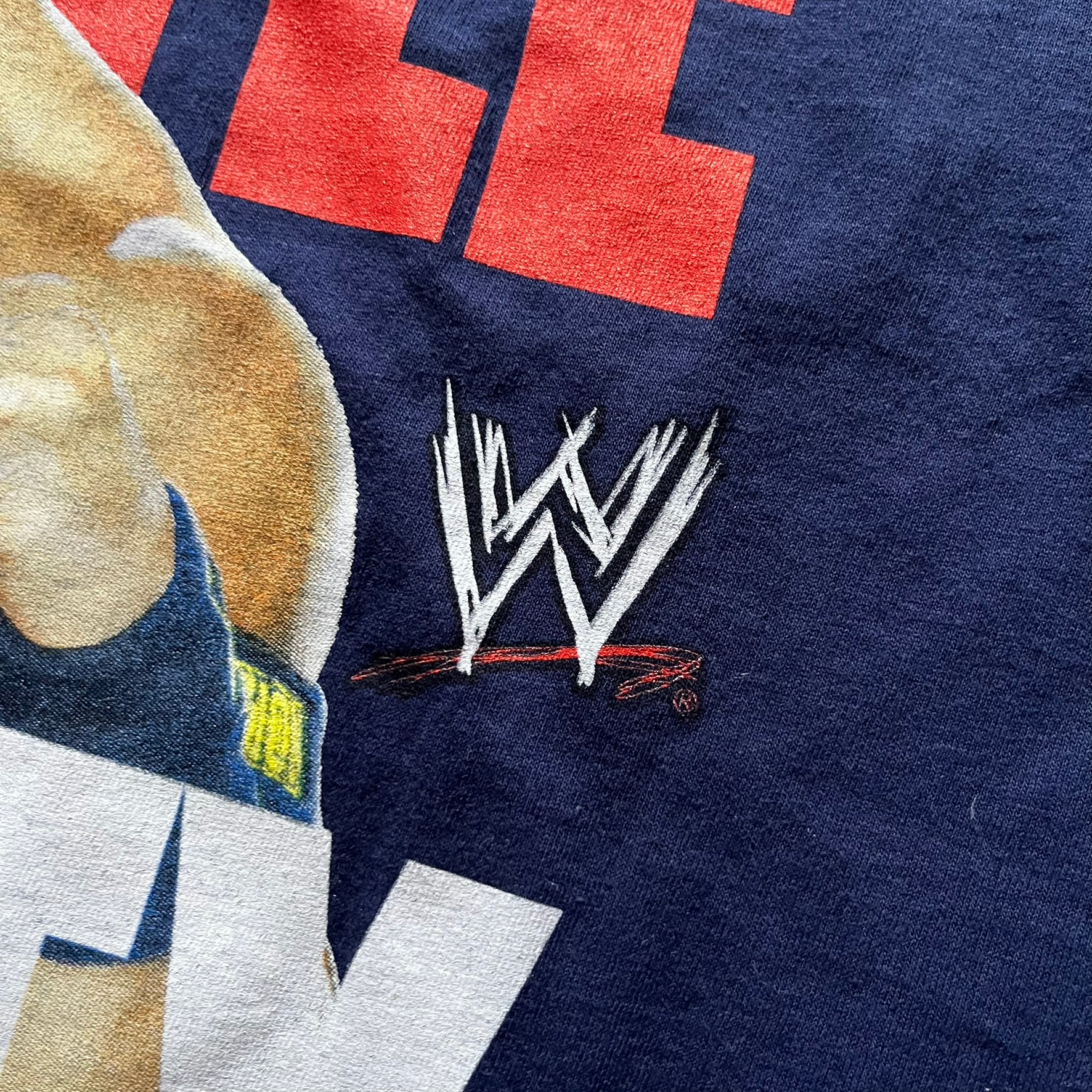 WWE John Cena “Hustle Loyalty Respect” Tee in navy, printed on a classic Screen Stars blank. Features a large front graphic of John Cena with big red, white, and blue lettering behind / in front of him and the WWE logo beside. A staple piece from Cena’s prime wrestling era.