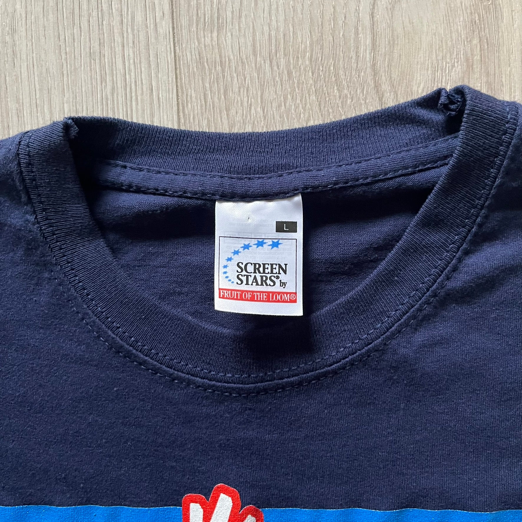 WWE John Cena “Hustle Loyalty Respect” Tee in navy, printed on a classic Screen Stars blank. Features a large front graphic of John Cena with big red, white, and blue lettering behind / in front of him and the WWE logo beside. A staple piece from Cena’s prime wrestling era.