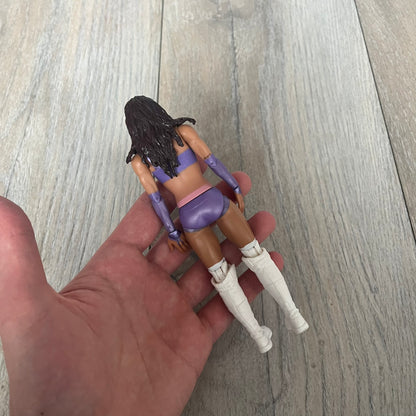 WWE Mattel Chelsea Green Series 122 Action Figure is a 6-inch articulated figure from the WWE Basic Series. It features approximately 10 points of articulation for poseability and includes TrueFX facial detailing for a more realistic appearance. The figure depicts Chelsea Green wearing purple ring attire paired with white high boots. It is designed to replicate WWE match action and display poses.