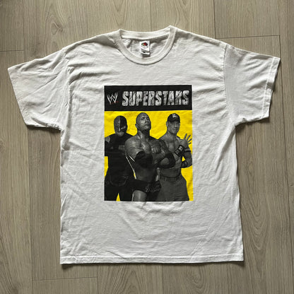 Vintage WWE Superstars Tee in white, highlighted by a large front print of wrestling icons The Rock, Rey Mysterio, and John Cena over a yellow base. Features the WWE logo and “Superstars” branding, printed on a Fruit of the Loom blank.