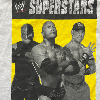 Vintage WWE Superstars Tee in white, highlighted by a large front print of wrestling icons The Rock, Rey Mysterio, and John Cena over a yellow base. Features the WWE logo and “Superstars” branding, printed on a Fruit of the Loom blank.