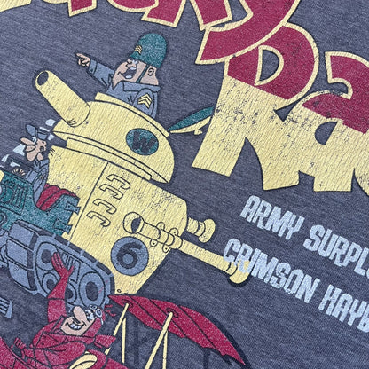 Wacky Races Gray 2010 Tee is a short-sleeve t-shirt featuring a front graphic with red and yellow “Wacky Races” text at the top. The design shows three cars at the starting line: the Army Surplus Special, the Crimson Haybaler, and the Mean Machine, each labeled with small white text next to the vehicles. The tee includes a purple Wacky Races neck tag with Cartoon Network 2010 licensing.