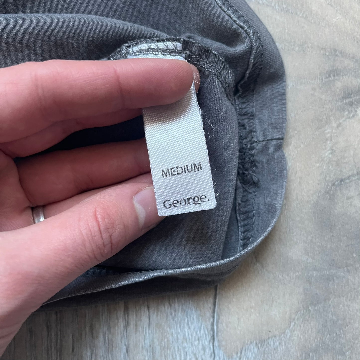 Wacky Races Gray 2010 Tee is a short-sleeve t-shirt featuring a front graphic with red and yellow “Wacky Races” text at the top. The design shows three cars at the starting line: the Army Surplus Special, the Crimson Haybaler, and the Mean Machine, each labeled with small white text next to the vehicles. The tee includes a purple Wacky Races neck tag with Cartoon Network 2010 licensing.