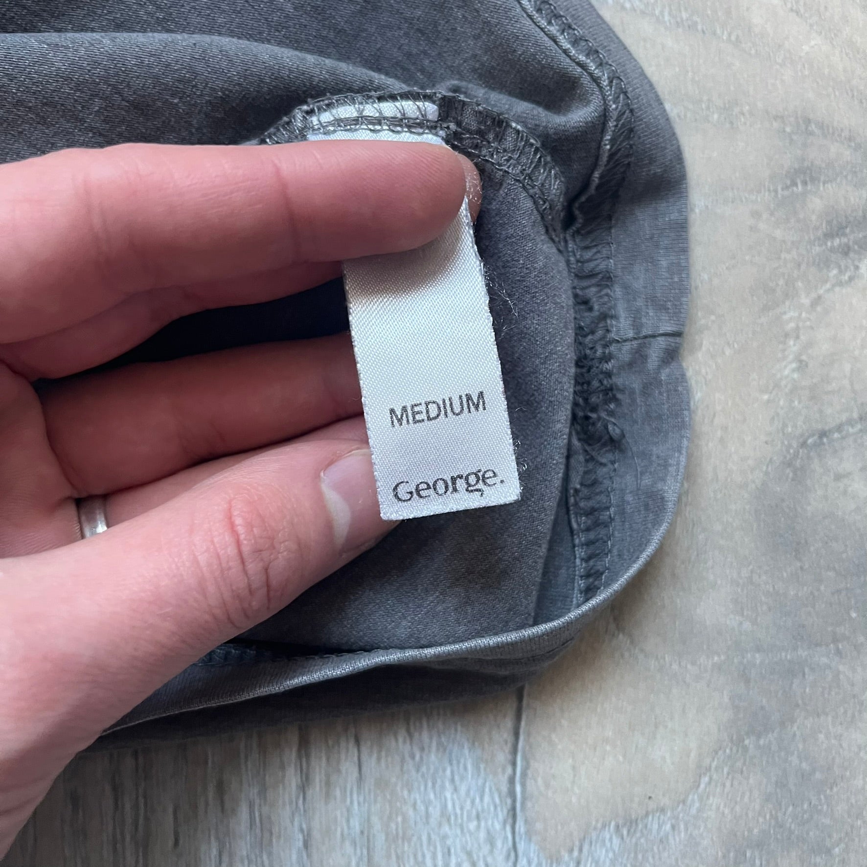 Wacky Races Gray 2010 Tee is a short-sleeve t-shirt featuring a front graphic with red and yellow “Wacky Races” text at the top. The design shows three cars at the starting line: the Army Surplus Special, the Crimson Haybaler, and the Mean Machine, each labeled with small white text next to the vehicles. The tee includes a purple Wacky Races neck tag with Cartoon Network 2010 licensing.