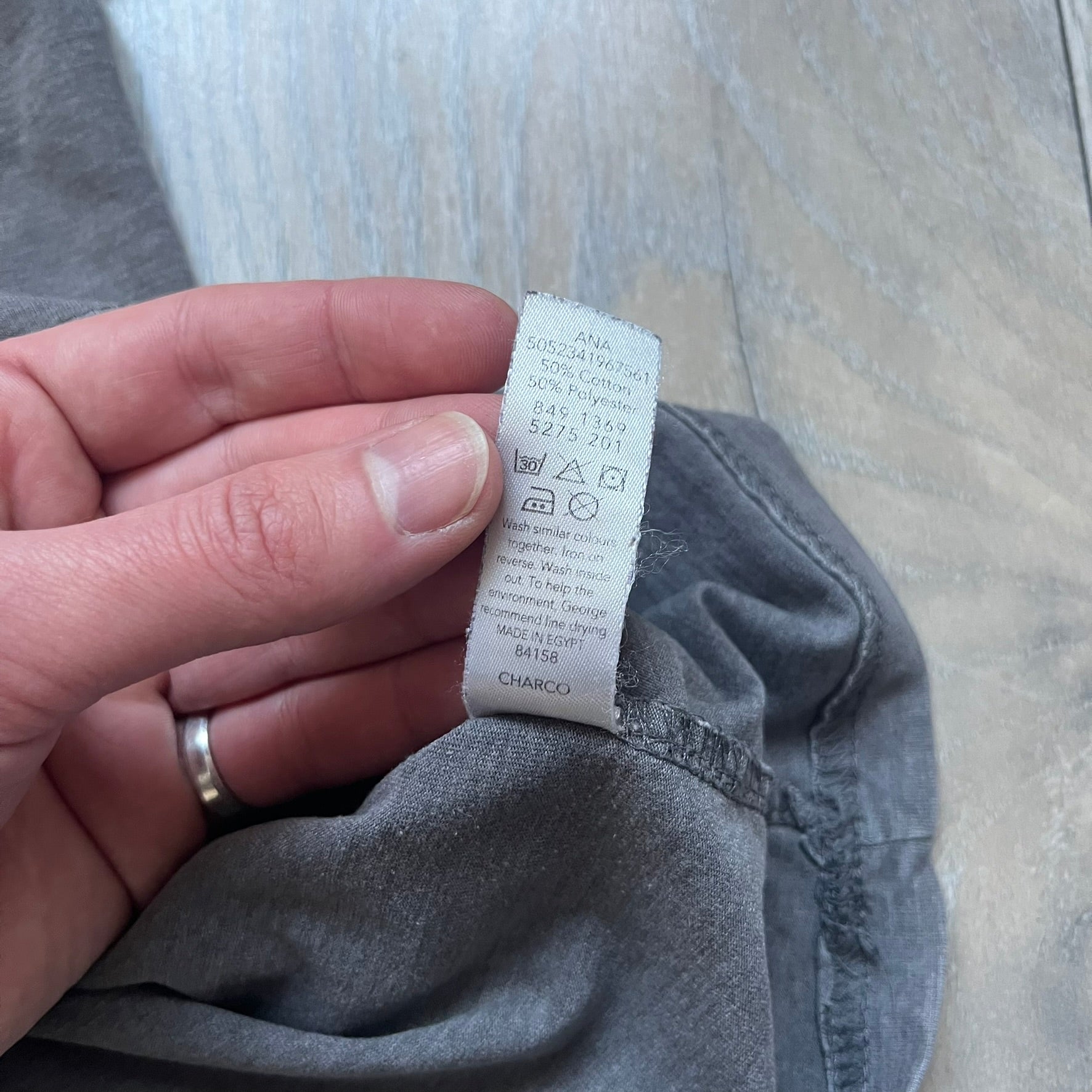 Wacky Races Gray 2010 Tee is a short-sleeve t-shirt featuring a front graphic with red and yellow “Wacky Races” text at the top. The design shows three cars at the starting line: the Army Surplus Special, the Crimson Haybaler, and the Mean Machine, each labeled with small white text next to the vehicles. The tee includes a purple Wacky Races neck tag with Cartoon Network 2010 licensing.