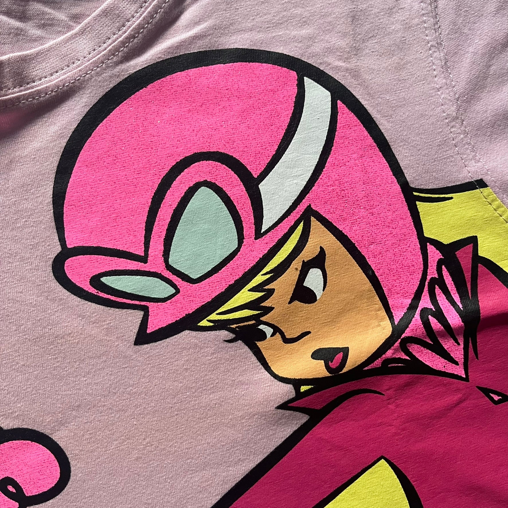 Baby pink 2013 Wacky Races women’s tee with Penelope Pitstop and her iconic "The Compact Pussycat" car. Glittery pink accents on her helmet, skirt, umbrella with white “Penelope Pitstop!” text. Officially Hanna-Barbera licensed.