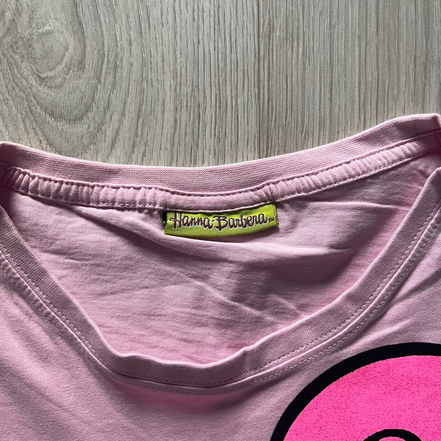 Baby pink 2013 Wacky Races women’s tee with Penelope Pitstop and her iconic "The Compact Pussycat" car. Glittery pink accents on her helmet, skirt, umbrella with white “Penelope Pitstop!” text. Officially Hanna-Barbera licensed.