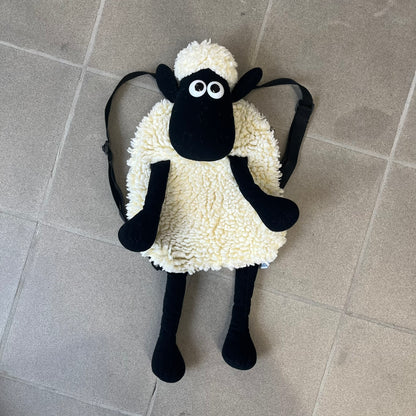 Wallace &amp; Gromit “Shaun The Sheep” 1990’s Backpack is a character-shaped backpack designed as Shaun the Sheep with black shoulder straps running from the bottom to the top of the body. The arms, legs, and ears are movable, and the face features plastic eyes. It includes one large main storage compartment, dating to the late 1980s-1990s production period.