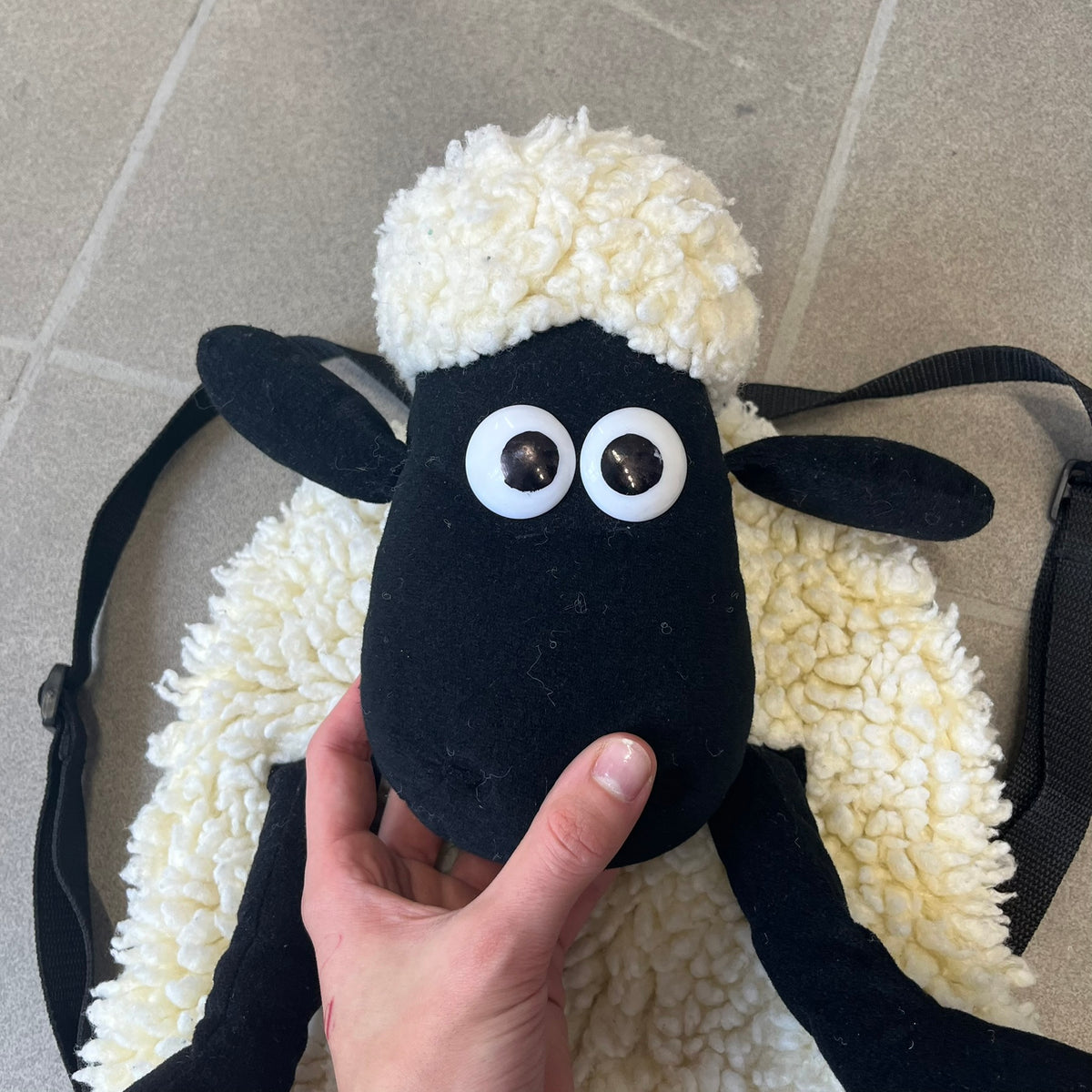 Wallace &amp; Gromit “Shaun The Sheep” 1990’s Backpack is a character-shaped backpack designed as Shaun the Sheep with black shoulder straps running from the bottom to the top of the body. The arms, legs, and ears are movable, and the face features plastic eyes. It includes one large main storage compartment, dating to the late 1980s-1990s production period.