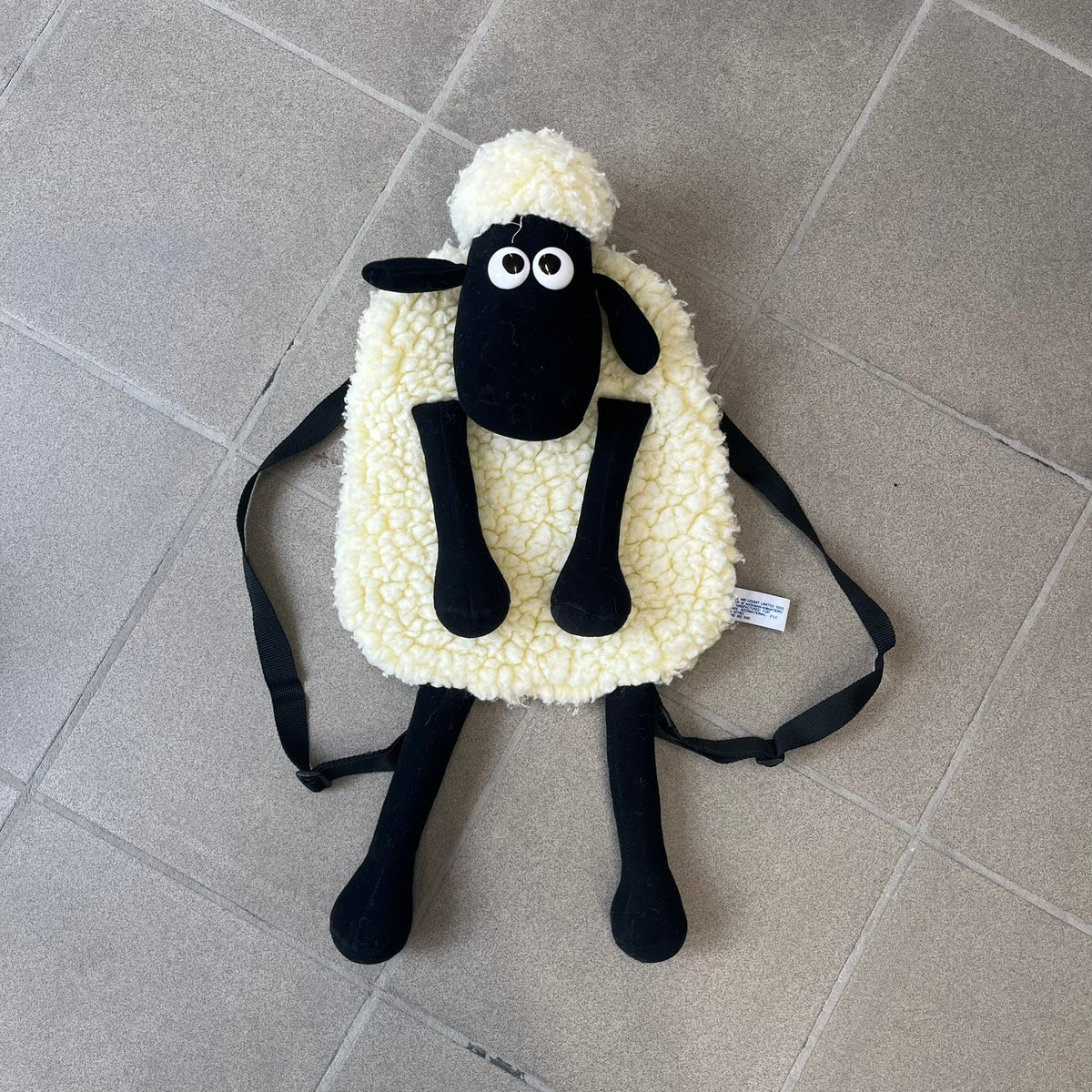 Wallace &amp; Gromit “Shaun The Sheep” 1990’s Backpack is a character-shaped backpack designed as Shaun the Sheep with black shoulder straps running from the bottom to the top of the body. The arms, legs, and ears are movable, and the face features plastic eyes. It includes one large main storage compartment, dating to the late 1980s-1990s production period.
