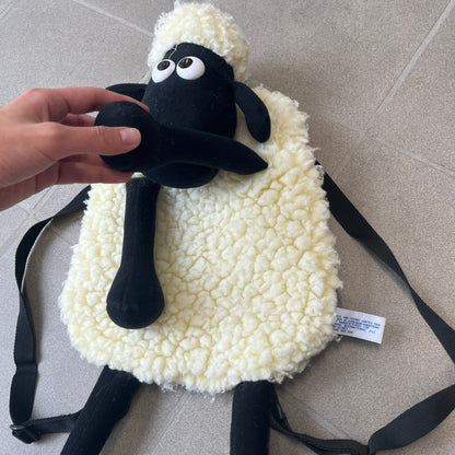 Wallace &amp; Gromit “Shaun The Sheep” 1990’s Backpack is a character-shaped backpack designed as Shaun the Sheep with black shoulder straps running from the bottom to the top of the body. The arms, legs, and ears are movable, and the face features plastic eyes. It includes one large main storage compartment, dating to the late 1980s-1990s production period.