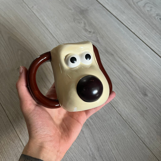 This 2005 Wallace &amp; Gromit ceramic mug captures the beloved character in full 3D detail, with protruding eyes and nose and an irregular sculpted form. One ear doubles as the handle, adding playful functionality to the design. Created exclusively for PG Tips, it’s finished with official licensing and copyright on the base.
