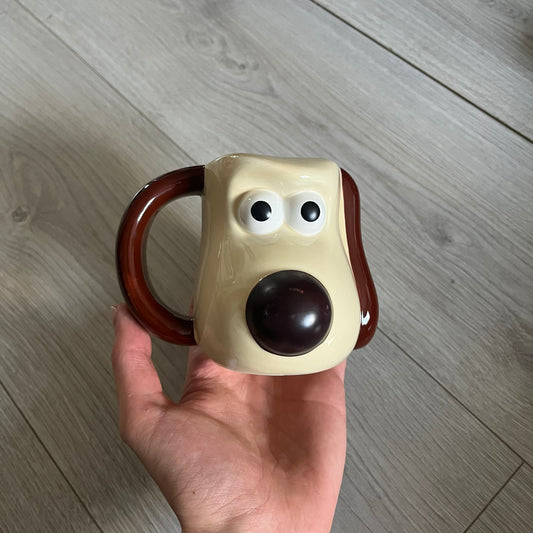 This 2005 Wallace &amp; Gromit ceramic mug captures the beloved character in full 3D detail, with protruding eyes and nose and an irregular sculpted form. One ear doubles as the handle, adding playful functionality to the design. Created exclusively for PG Tips, it’s finished with official licensing and copyright on the base.