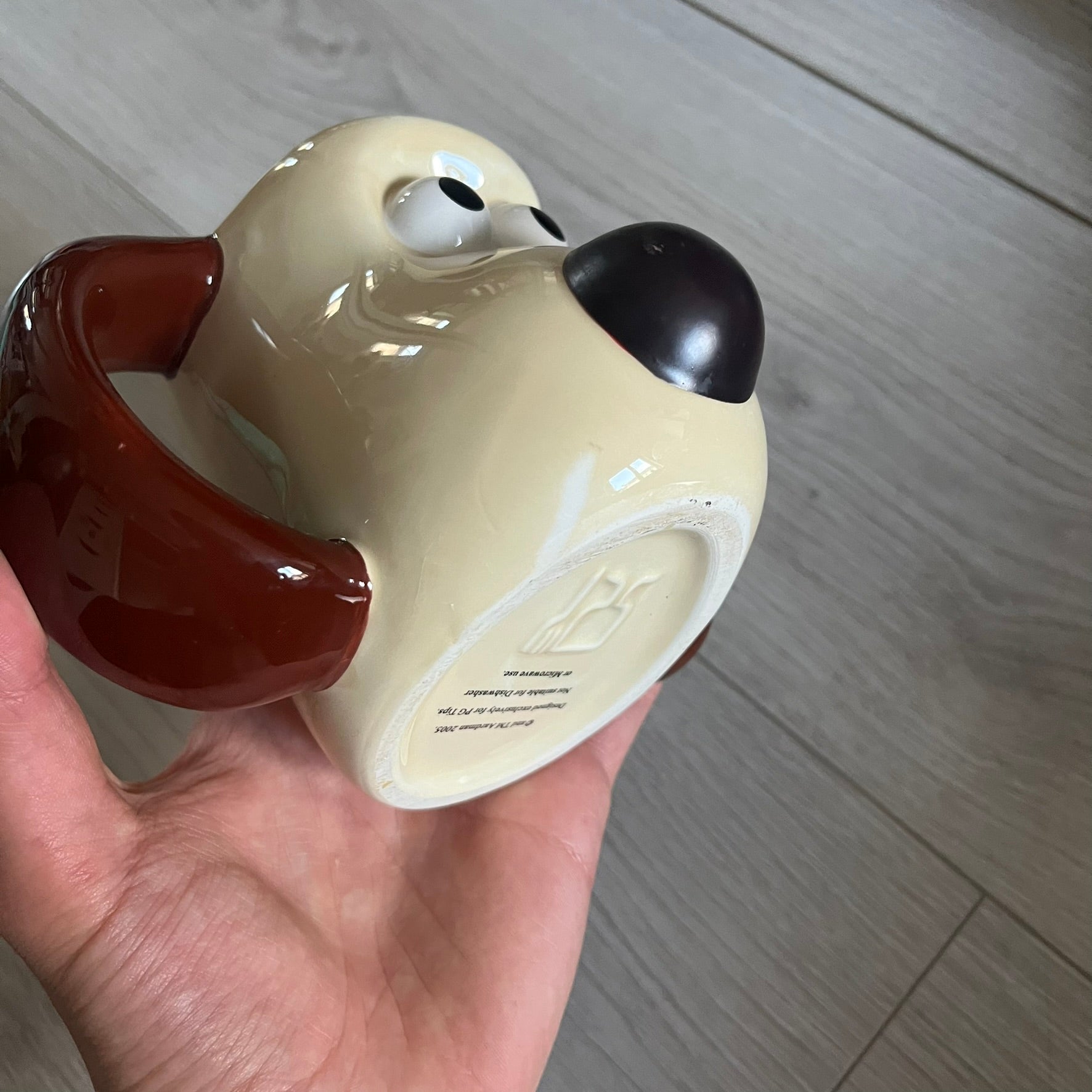 This 2005 Wallace &amp; Gromit ceramic mug captures the beloved character in full 3D detail, with protruding eyes and nose and an irregular sculpted form. One ear doubles as the handle, adding playful functionality to the design. Created exclusively for PG Tips, it’s finished with official licensing and copyright on the base.