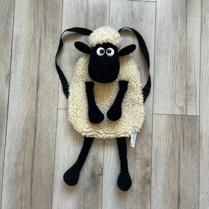 Wallace &amp; Gromit “Shaun The Sheep” 1990’s Backpack is a character-shaped backpack designed as Shaun the Sheep with black shoulder straps running from the bottom to the top of the body. The arms, legs, and ears are movable, and the face features plastic eyes. It includes one large main storage compartment, and a tag dating to the late 1980s-1990s production period.