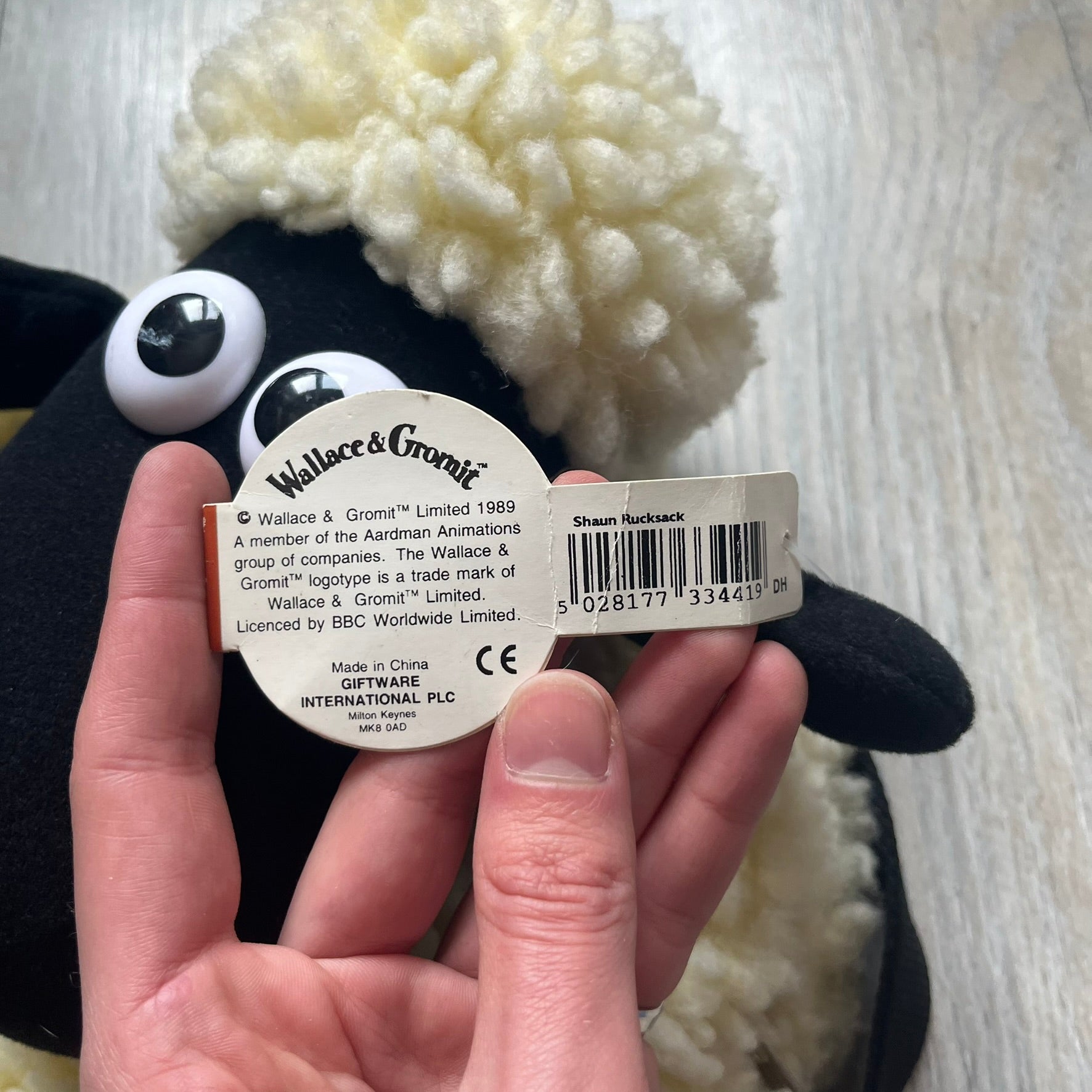 Wallace &amp; Gromit “Shaun The Sheep” 1990’s Backpack is a character-shaped backpack designed as Shaun the Sheep with black shoulder straps running from the bottom to the top of the body. The arms, legs, and ears are movable, and the face features plastic eyes. It includes a Wallace &amp; Gromit paper tag, a material tag, and one large main storage compartment, dating to the late 1980s-1990s production period.