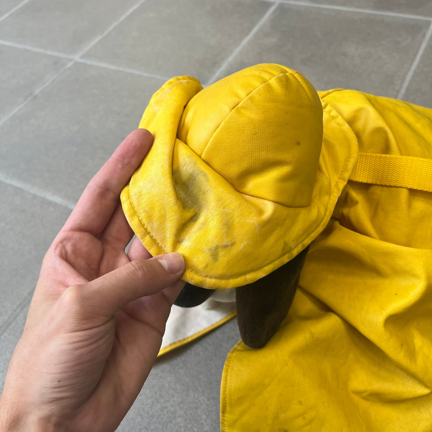 The Wallace and Gromit Gromit Plush Backpack is a 1990s licensed item produced by Aardman Animations. It features Gromit dressed in his bright yellow PVC raincoat and matching hat, as seen in The Wrong Trousers. The backpack is made from soft plush fabric with plastic eyes, a hard black nose, and a genuine stamp confirming official production. The bag opens from the side and includes adjustable shoulder straps for wearability.