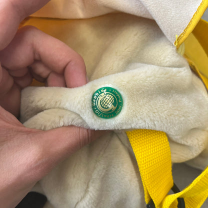 The Wallace and Gromit Gromit Plush Backpack is a 1990s licensed item produced by Aardman Animations. It features Gromit dressed in his bright yellow PVC raincoat and matching hat, as seen in The Wrong Trousers. The backpack is made from soft plush fabric with plastic eyes, a hard black nose, and a genuine stamp confirming official production. The bag opens from the side and includes adjustable shoulder straps for wearability.