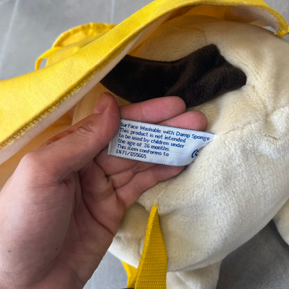 The Wallace and Gromit Gromit Plush Backpack is a 1990s licensed item produced by Aardman Animations. It features Gromit dressed in his bright yellow PVC raincoat and matching hat, as seen in The Wrong Trousers. The backpack is made from soft plush fabric with plastic eyes, a hard black nose, and a genuine stamp confirming official production. The bag opens from the side and includes adjustable shoulder straps for wearability.
