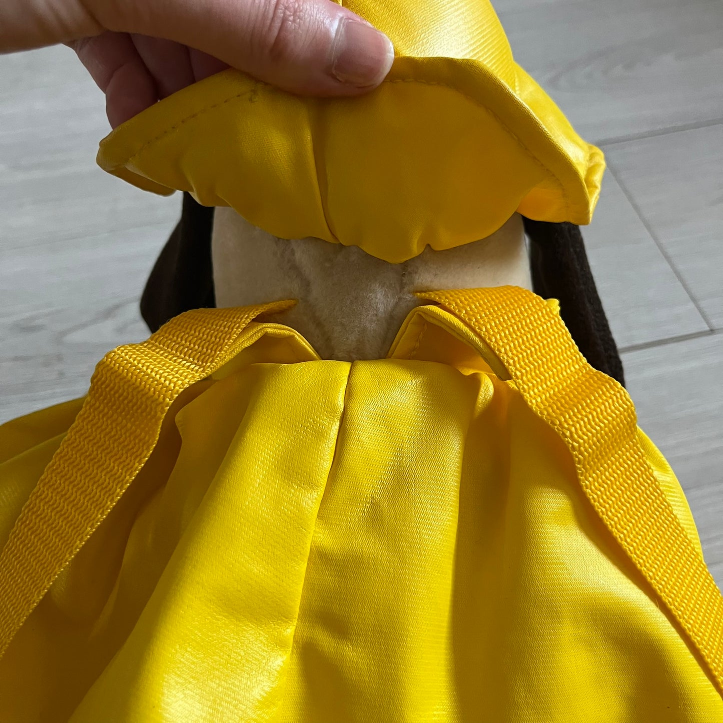 The Wallace and Gromit Gromit Plush Backpack is a 1990s licensed item produced by Aardman Animations. It features Gromit dressed in his bright yellow PVC raincoat and matching hat, as seen in The Wrong Trousers. The backpack is made from soft plush fabric with plastic eyes, a hard black nose, and a genuine stamp confirming official production. The bag opens from the side and includes adjustable shoulder straps for wearability