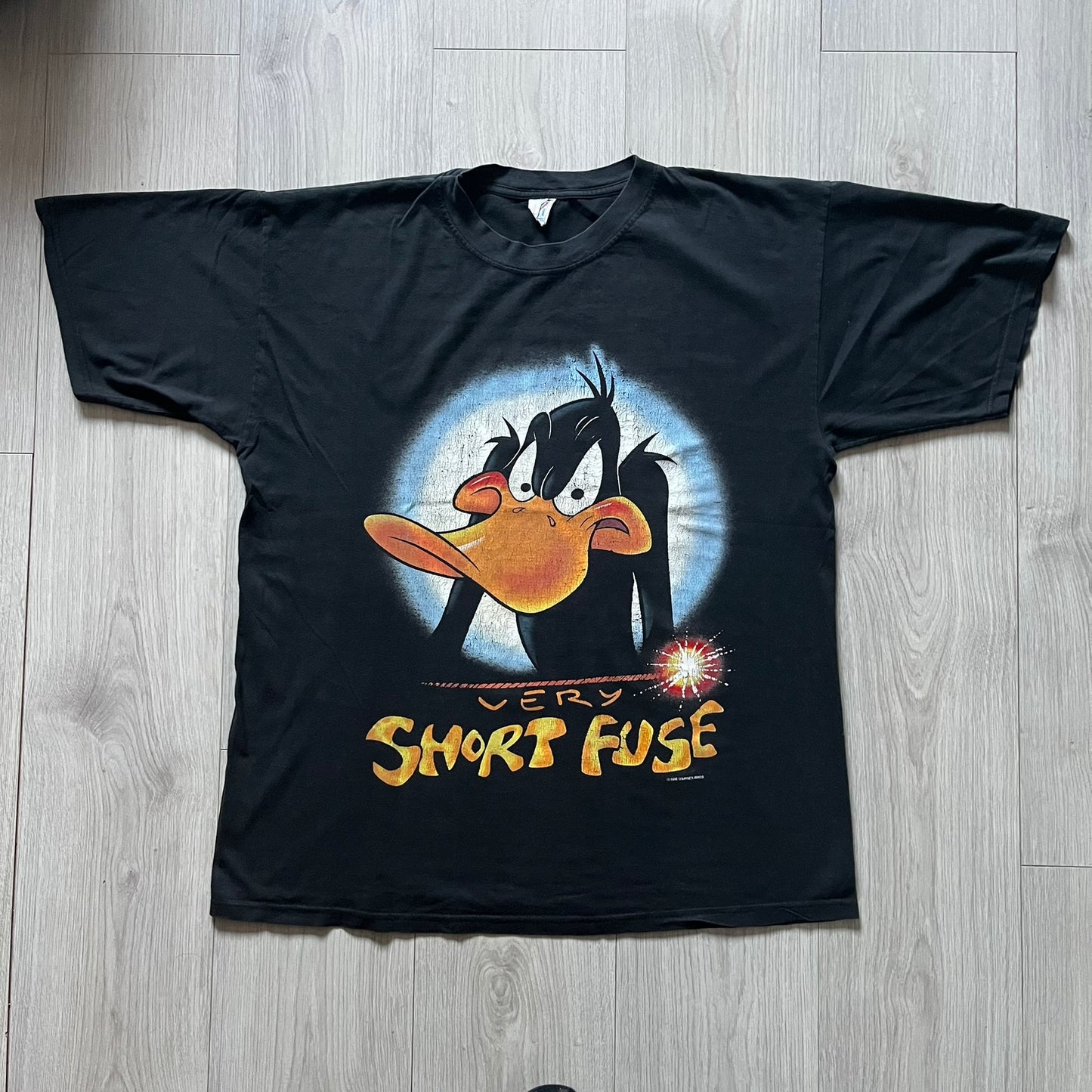 Black Warner Bros 1996 Daffy Duck ‘Very Short Fuse’ Tee showcasing a classic angry Daffy graphic and yellow text on the front. Vintage 1996 licensed Warner Bros merchandise with high-quality print details.