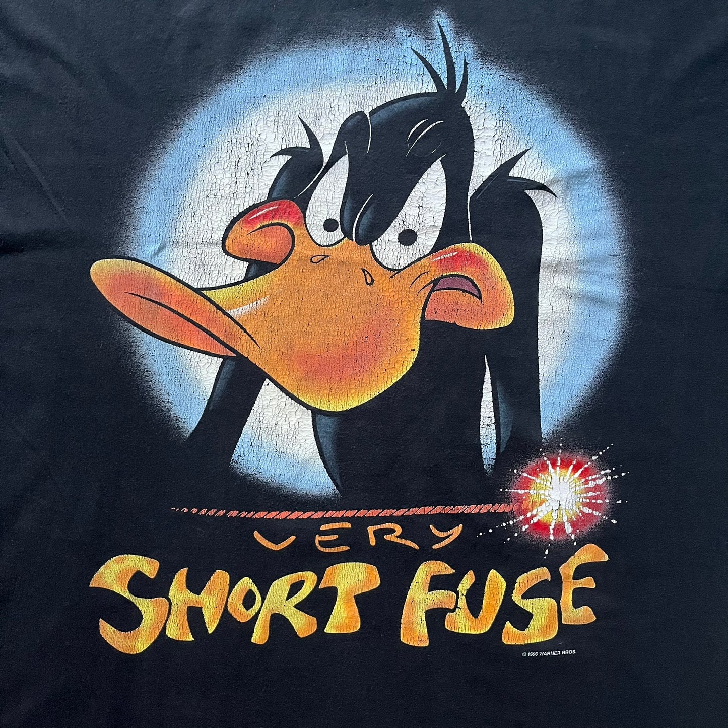 Black Warner Bros 1996 Daffy Duck ‘Very Short Fuse’ Tee showcasing a classic angry Daffy graphic and yellow text on the front. Vintage 1996 licensed Warner Bros merchandise with high-quality print details.