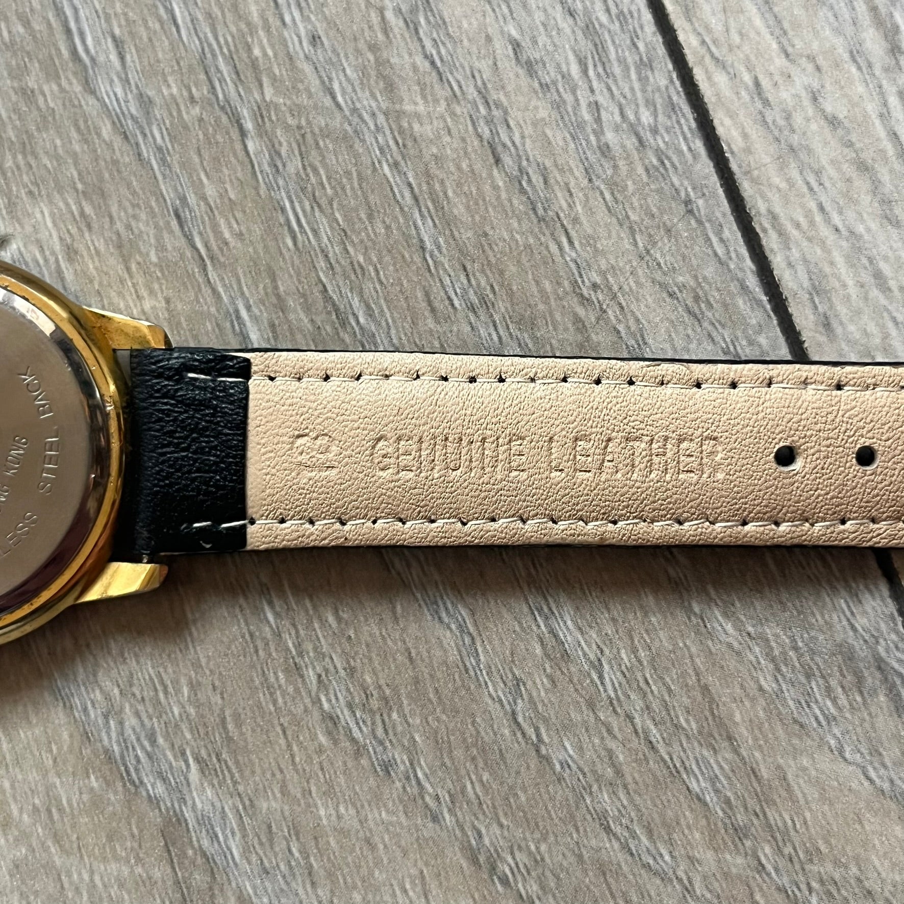 Warner Bros Sylvester 1990 Analog Watch features a gold-tone case with a white dial and black leather strap marked as genuine leather. The dial displays Sylvester with vertical “Sylvester” text, along with hour markers at 12, 3, 6, and 9. The watch uses a Japan movement and includes Warner Bros 1990 licensing engraved on the caseback