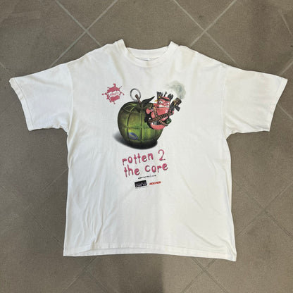 Worms 2 “Rotten 2 The Core” 1997 Tee is a white T-shirt with a front graphic of an apple styled like a grenade, with an angry worm holding a gun coming out of it. The Worms 2 logo sits to the left, and red “Rotten 2 The Core” text below the apple is followed by the website and company logos and a small 1997 licensing mark.