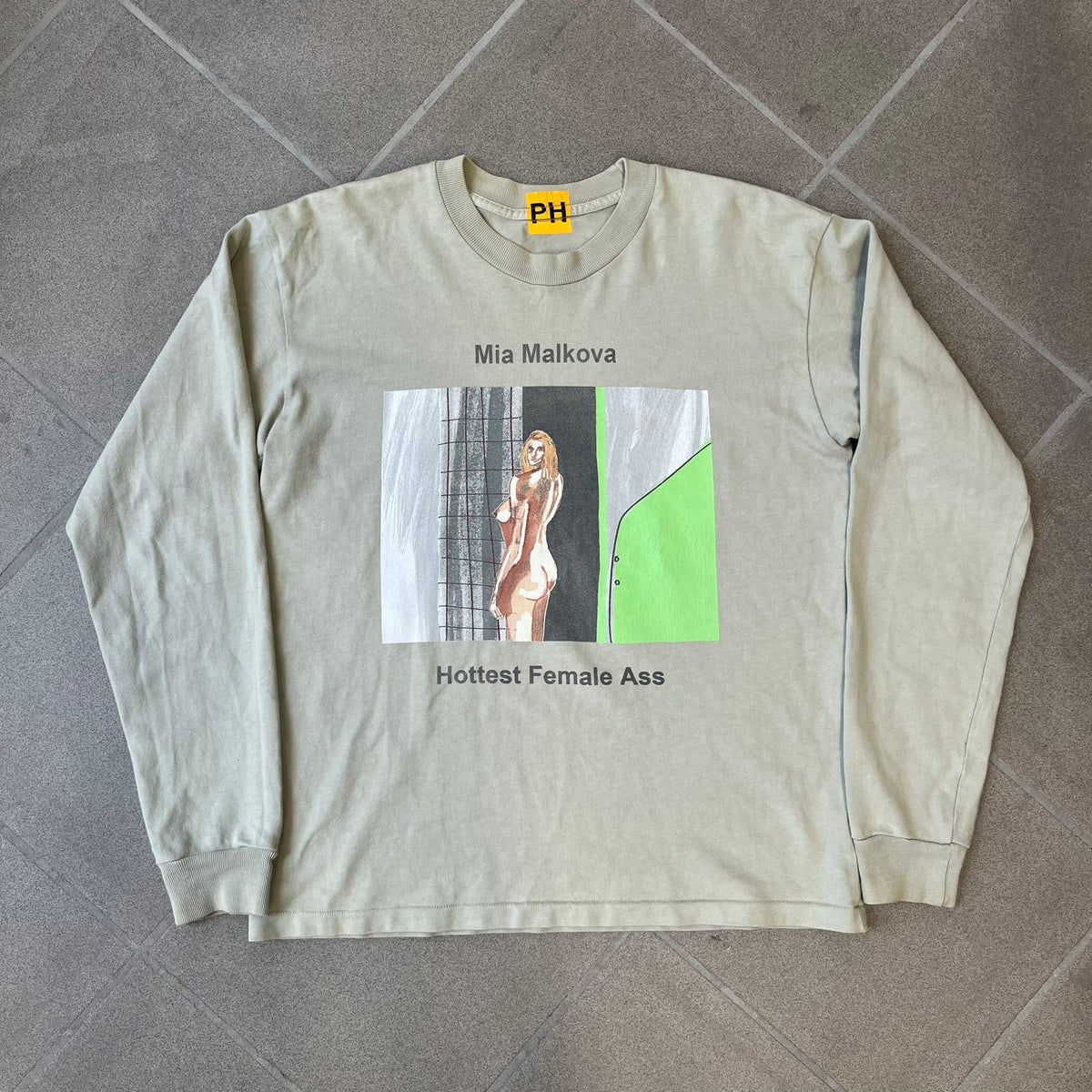Longsleeve tee from the FW18 Yeezy x Pornhub collection, released 09/07/2018. Vapor color, featuring a front illustration of painted Mia Malkova with her name above and “Hottest Female Ass” below. Back has the numbers “6918” (futuristic theme set in the year 6918). Includes printed Pornhub tag and YEEZY wash tag, part of a limited run commemorating the 2018 Pornhub Awards.