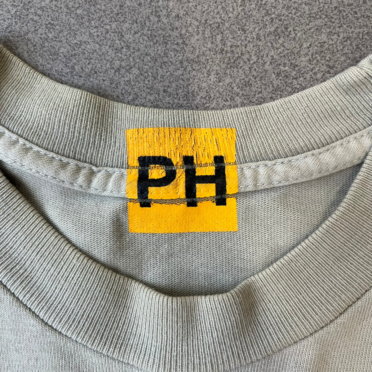 Longsleeve tee from the FW18 Yeezy x Pornhub collection, released 09/07/2018. Vapor color, featuring a front illustration of painted Mia Malkova with her name above and “Hottest Female Ass” below. Back has the numbers “6918” (futuristic theme set in the year 6918). Includes printed Pornhub tag and YEEZY wash tag, part of a limited run commemorating the 2018 Pornhub Awards.