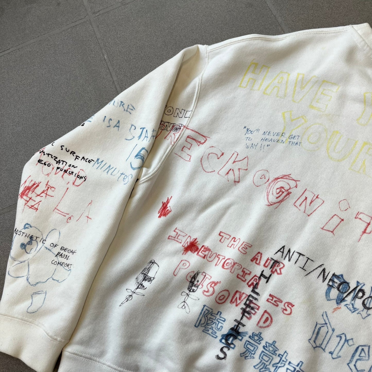 Yeezy Season 5 Scribbled Adidas Crewneck by ERD features an oversized, boxy silhouette in the Arctic colorway. The 100% cotton Adidas crewneck has handwritten-style printed graphics and phrases across the garment, including a embroidered Adidas Three Stripes logo on the chest. It was made in Italy and designed by Henri Alexander Levy from Enfants Riches Déprimés.