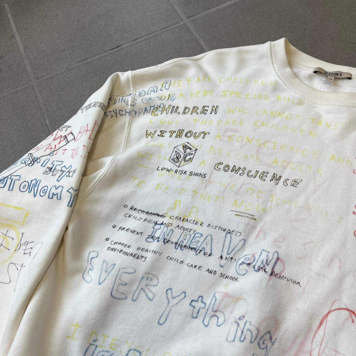 Yeezy Season 5 Scribbled Adidas Crewneck by ERD features an oversized, boxy silhouette in the Arctic colorway. The 100% cotton Adidas crewneck has handwritten-style printed graphics and phrases across the garment, including a embroidered Adidas Three Stripes logo on the chest. It was made in Italy and designed by Henri Alexander Levy from Enfants Riches Déprimés.