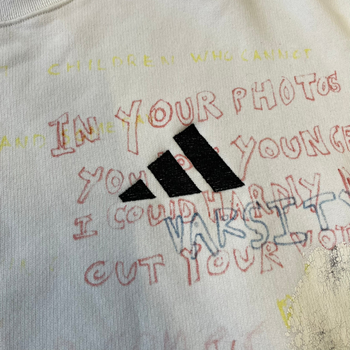 Yeezy Season 5 Scribbled Adidas Crewneck by ERD features an oversized, boxy silhouette in the Arctic colorway. The 100% cotton Adidas crewneck has handwritten-style printed graphics and phrases across the garment, including a embroidered Adidas Three Stripes logo on the chest. It was made in Italy and designed by Henri Alexander Levy from Enfants Riches Déprimés.
