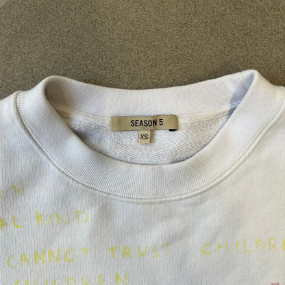 Yeezy Season 5 Scribbled Adidas Crewneck by ERD features an oversized, boxy silhouette in the Arctic colorway. The 100% cotton Adidas crewneck has handwritten-style printed graphics and phrases across the garment, including a embroidered Adidas Three Stripes logo on the chest. It was made in Italy and designed by Henri Alexander Levy from Enfants Riches Déprimés.